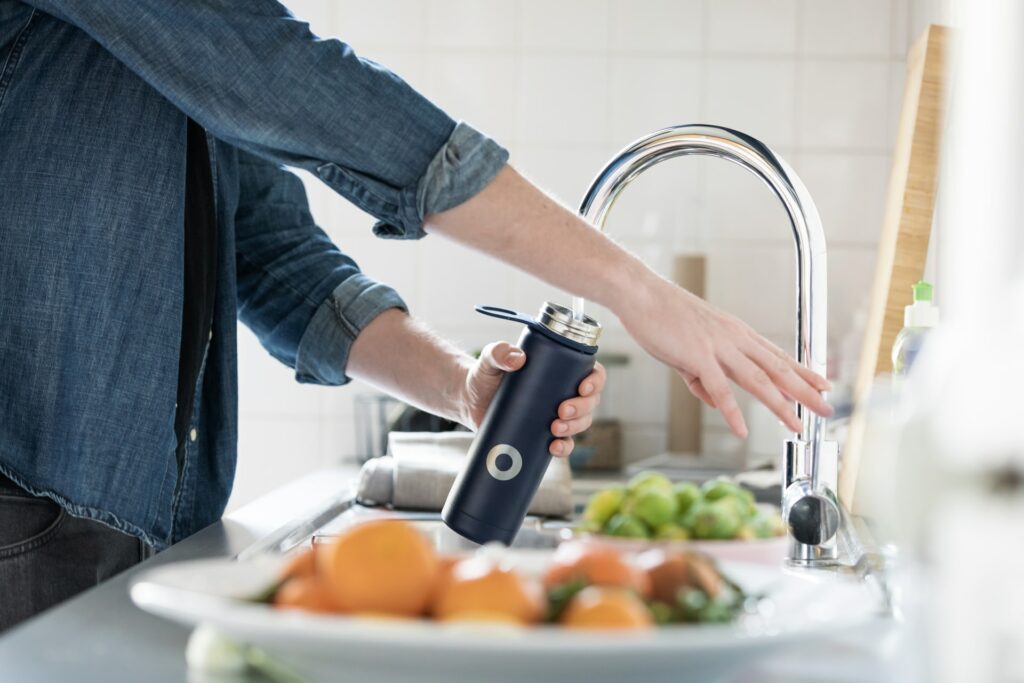 Reusable water bottle being filled at the tap